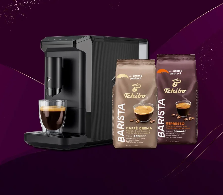 Siyah kahve makinesi, bir bardak kahve ve iki paket Tchibo Barista kahve çekirdeği: Caffè Crema ve Espresso.