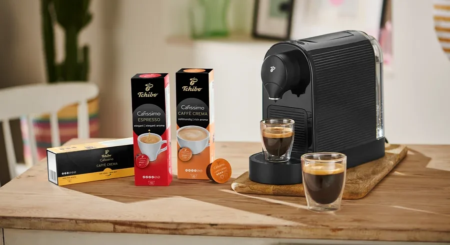 Siyah bir Cafissimo pure+ kahve makinesi, yanında iki bardak kahve ile birlikte ahşap bir tahta üzerinde duruyor.