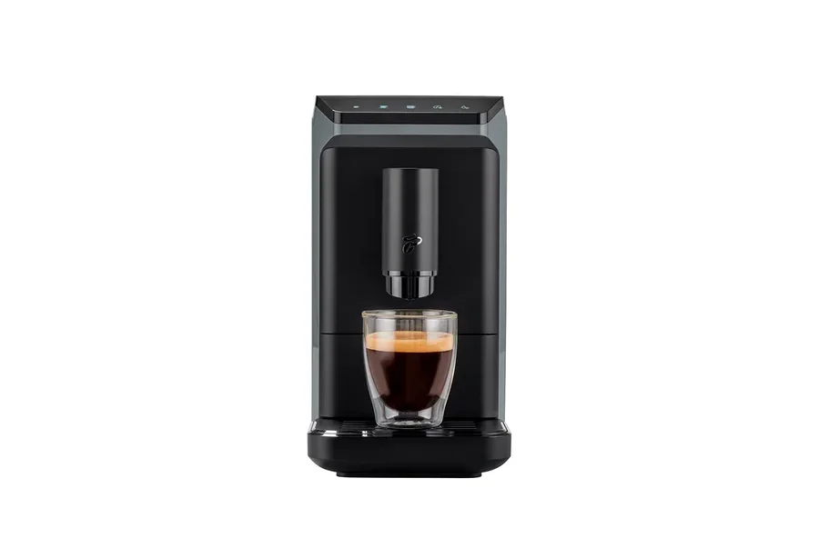 Altında bir bardak espresso bulunan siyah bir kahve makinesi.