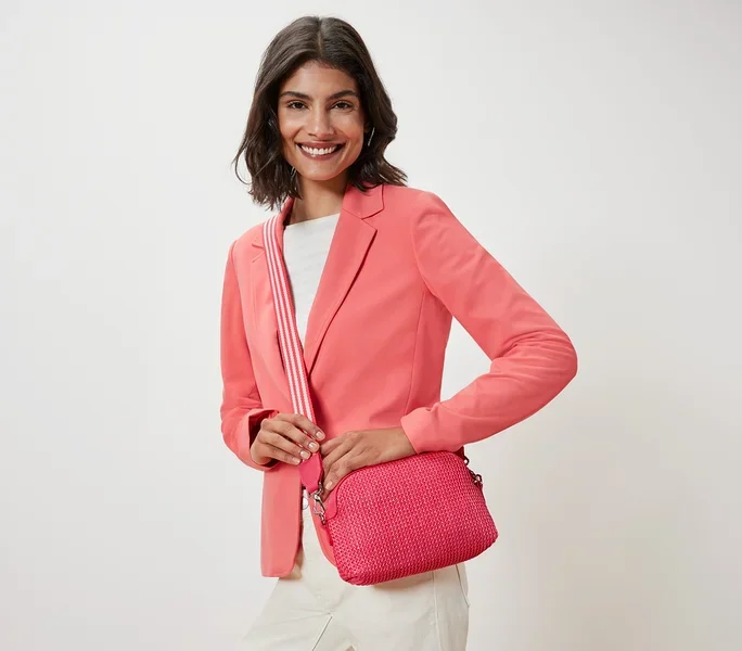 Pembe ceketli kadın, pembe omuz çantası tutuyor.