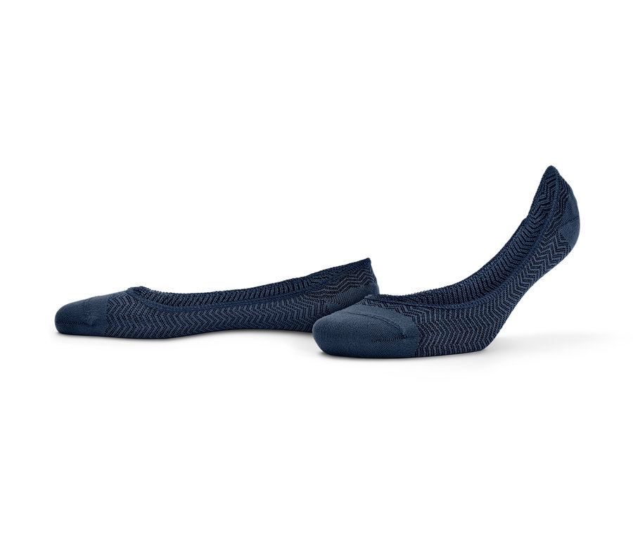 Açık renkli bir zeminde duran iki çift mavi sneaker çorabı.
