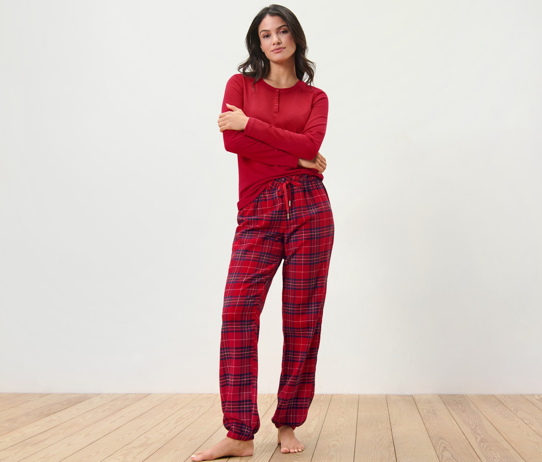 Kadın kareli, kırmızı flanel pijama takımıyla poz veriyor.