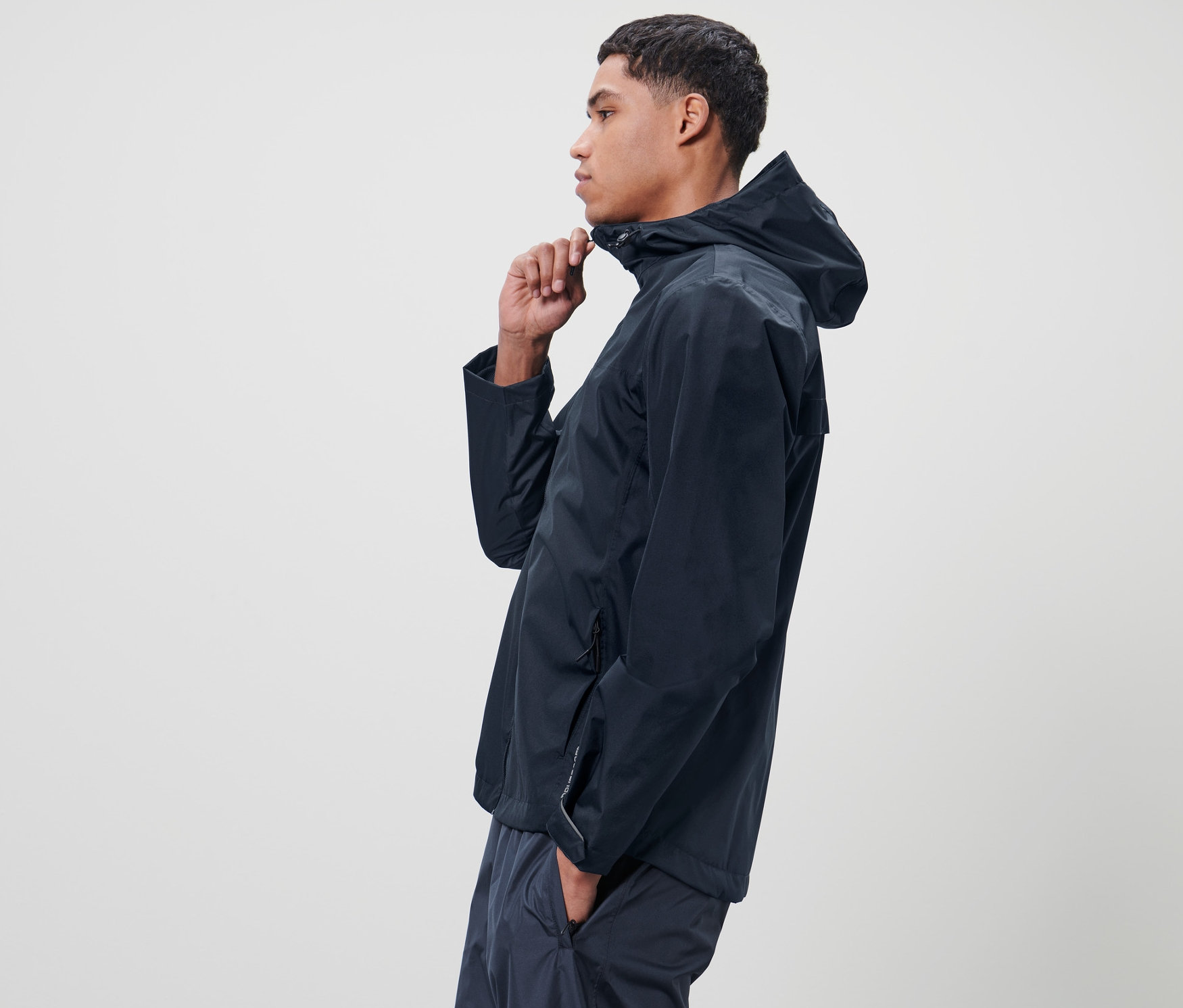 Adam mavi Unisex Yağmurluğu kapatıyor.