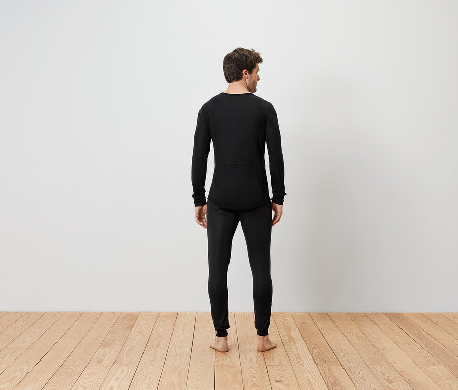 Siyah termal içlik giymiş, arkası dönük bir adam ayakta duruyor.