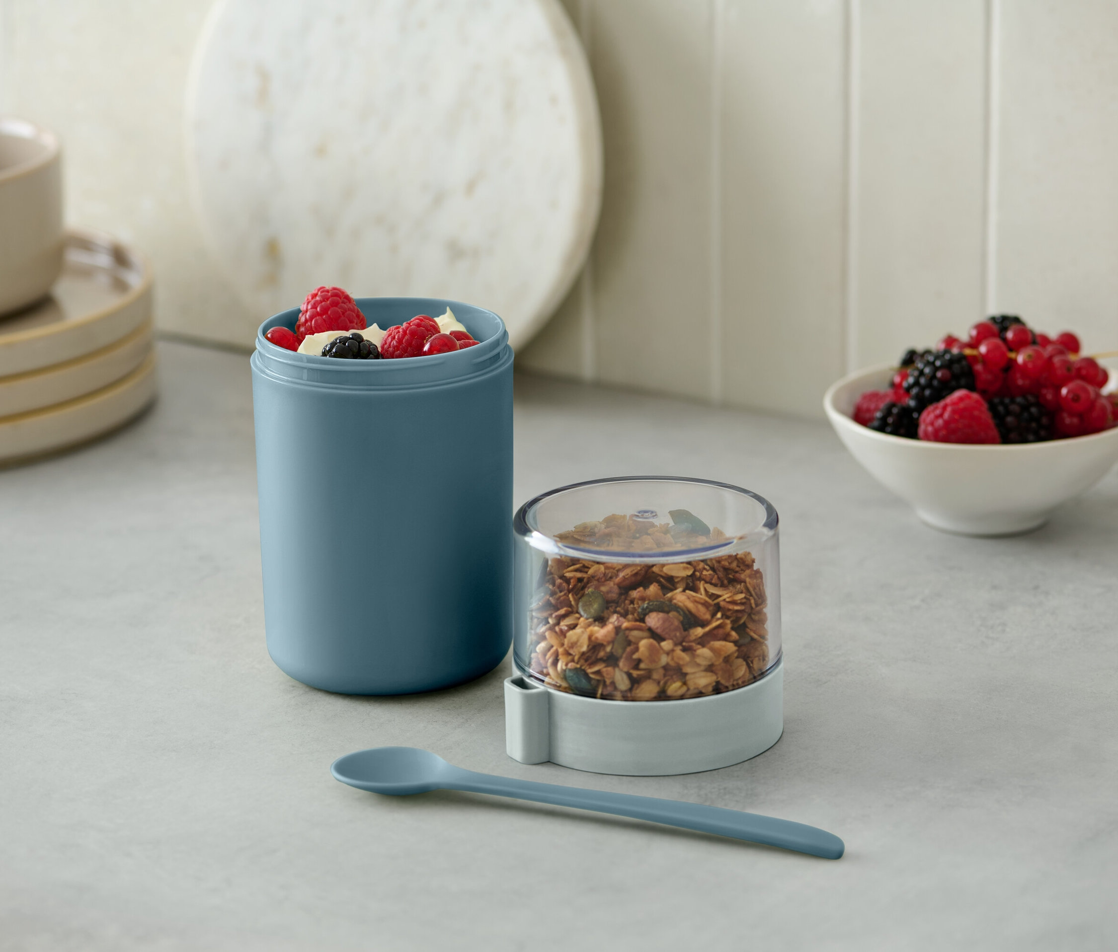 Yeşil renkli, müsli ve meyvelerle dolu taşınabilir yoğurt kabı.