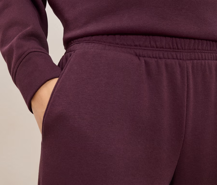 Bordo eşofman altı ve sweatshirt yakın çekim. Bir el pantolonun cebinde.