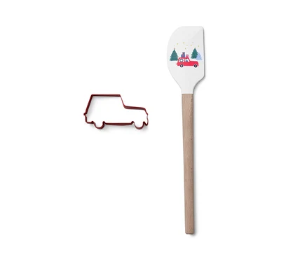 Kırmızı araba şeklinde kurabiye kalıbı, araba baskılı beyaz hamur spatulasının yanında duruyor.