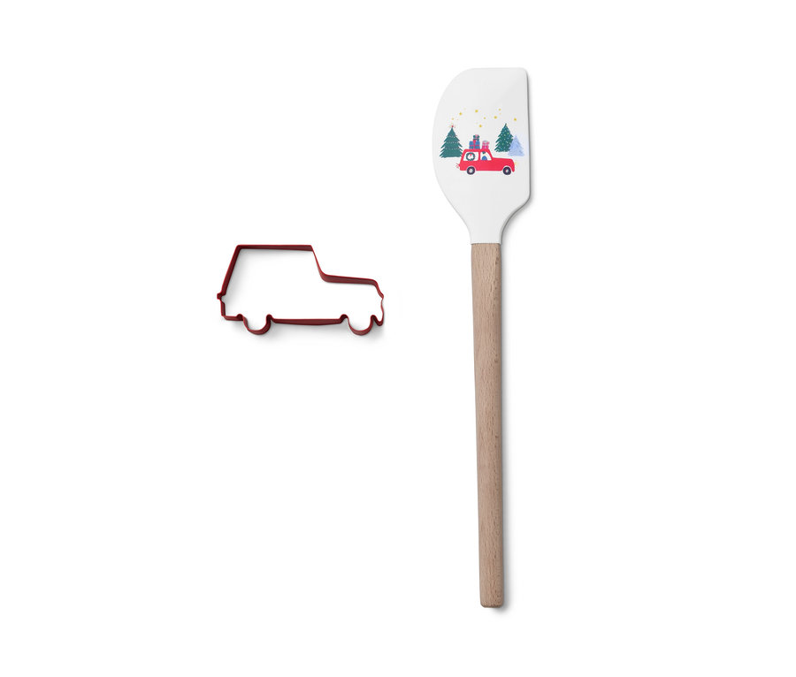Kırmızı araba şeklinde kurabiye kalıbı, araba baskılı beyaz hamur spatulasının yanında duruyor.