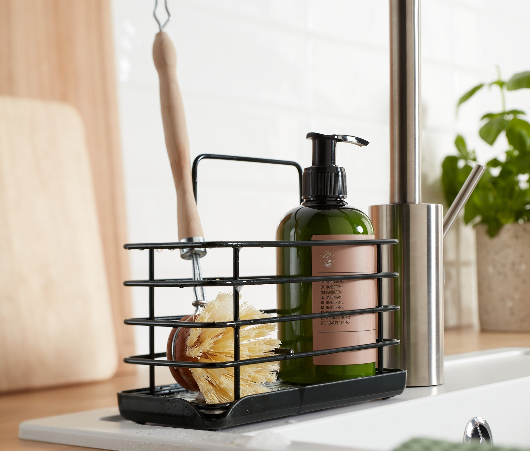 Lavabonun üzerinde fırça ve sabun şişesi olan siyah metal bulaşık malzemesi standı.