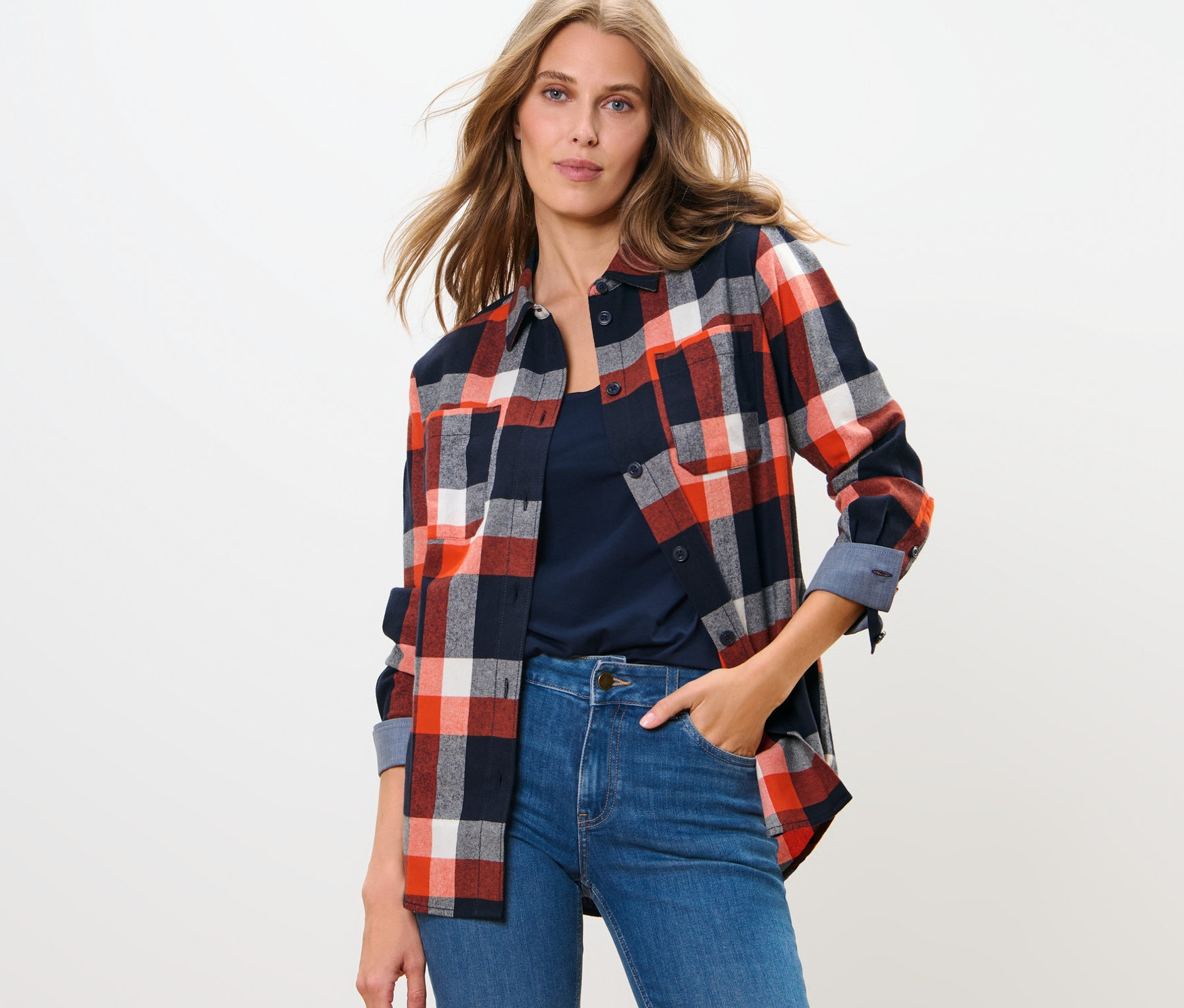 Kadın kareli gömlek ve kot pantolonla poz veriyor.
