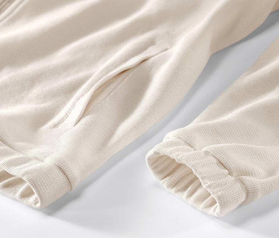 Krem rengi, fermuarlı ve cepli sweat montun yakın çekimi.