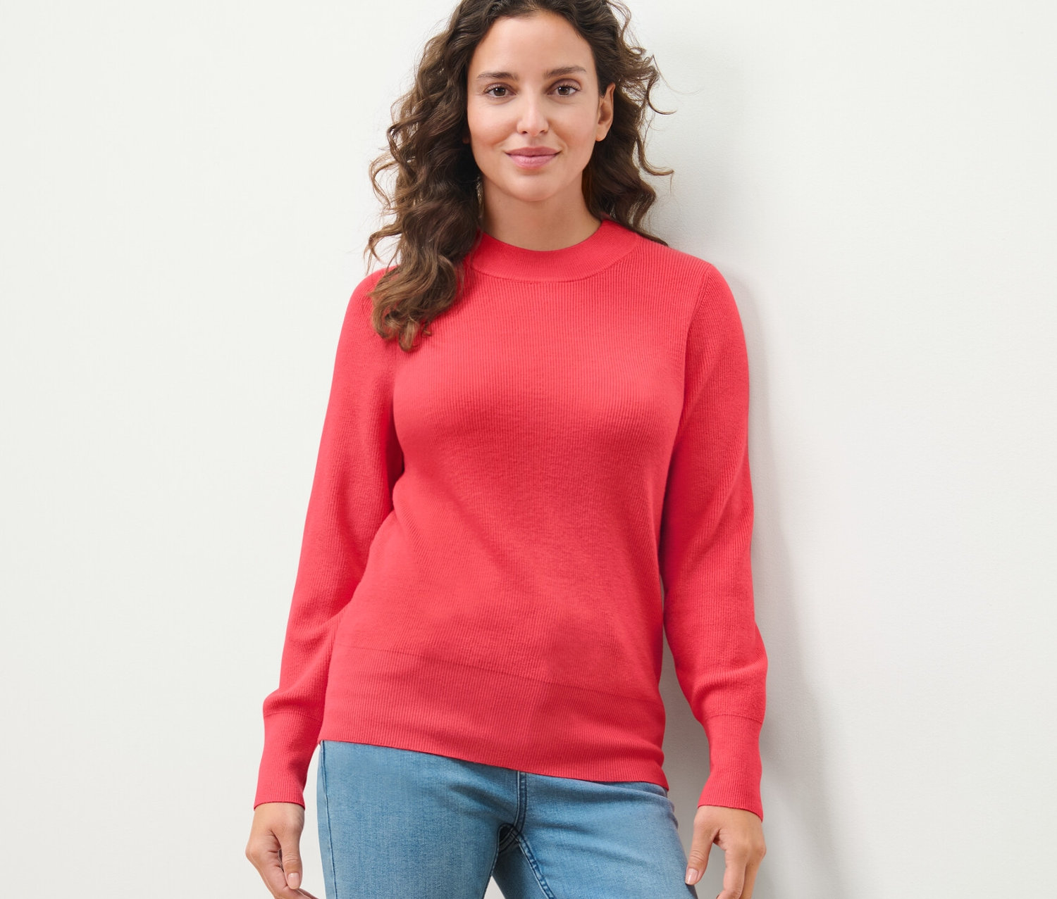 Kadın ince örgülü bir kazakla poz veriyor.