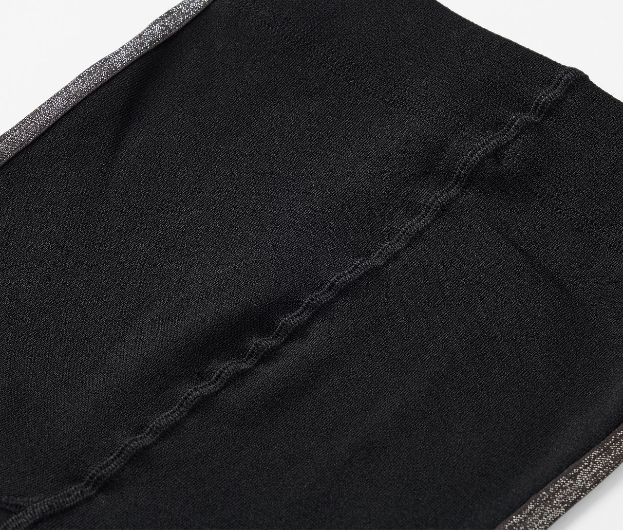 Yan tarafında gri şerit bulunan siyah tayt detayı.