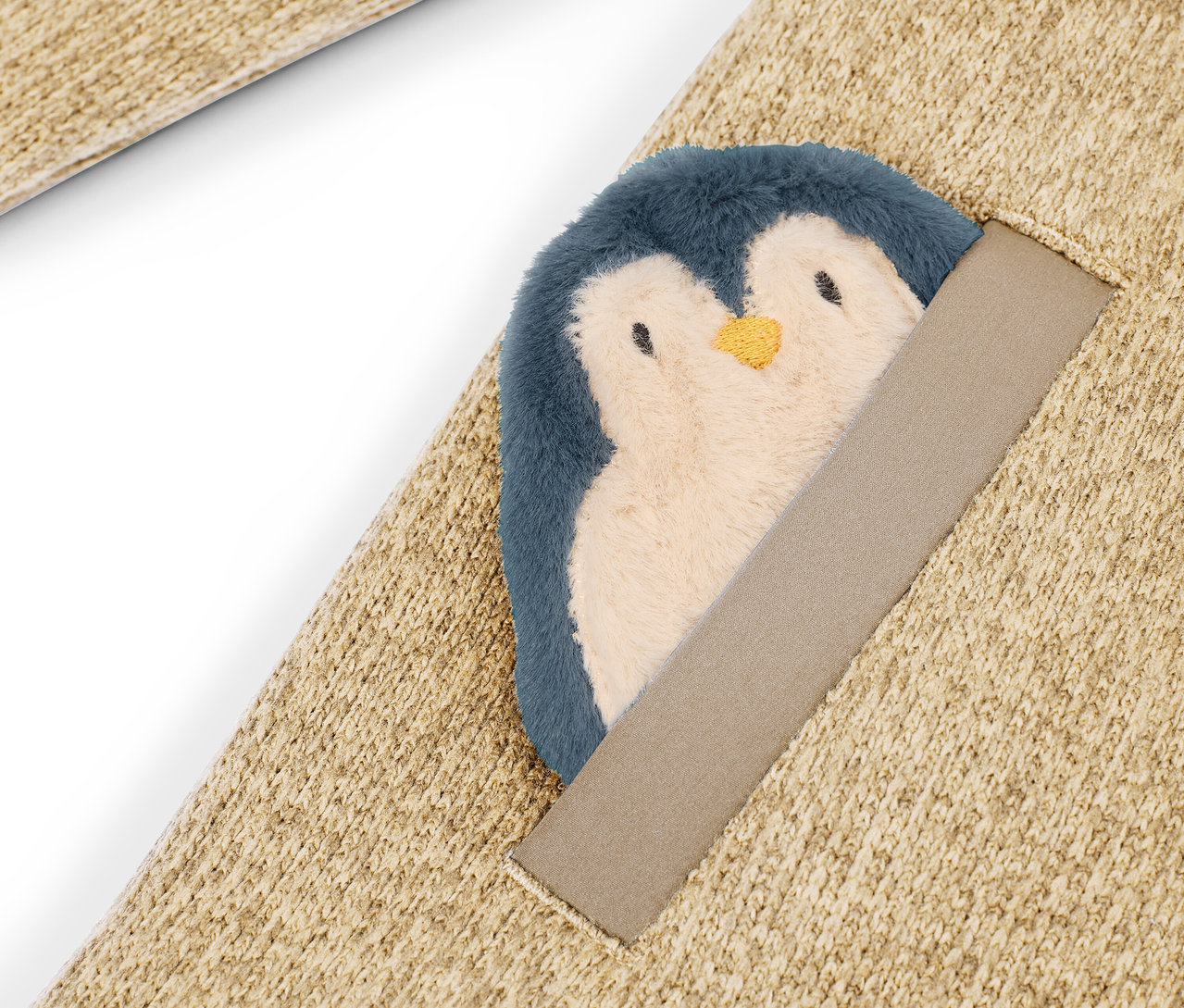 Bej rengi halının üzerine dikilmiş peluş penguen detayı.