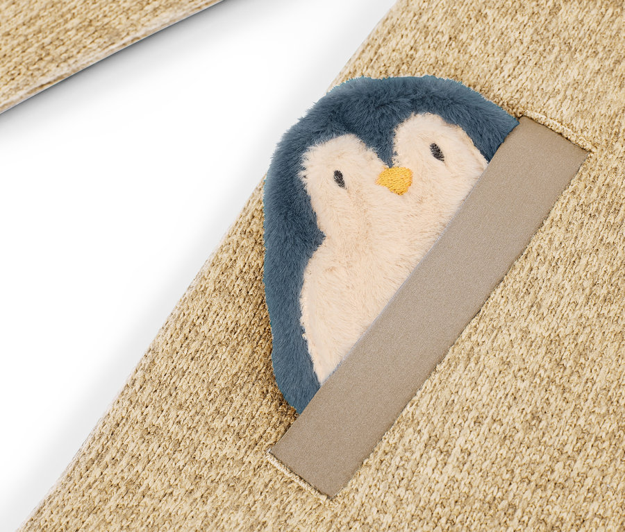 Bej rengi halının üzerine dikilmiş peluş penguen detayı.