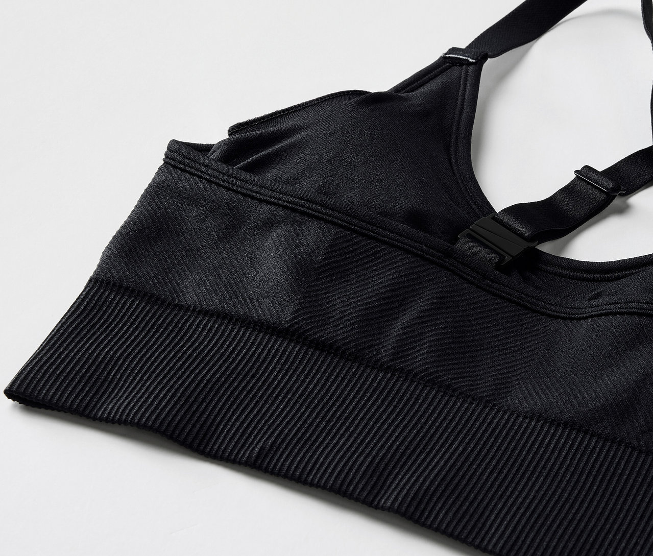 Ayarlanabilir askılı ve fitilli kenarlı siyah bir spor sutyeninin yakın çekim görüntüsü.