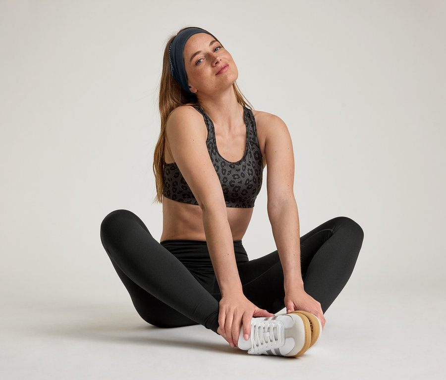 Kadın bağdaş kurmuş oturuyor ve Spor Tayt »ActiveSoft« giyiyor.