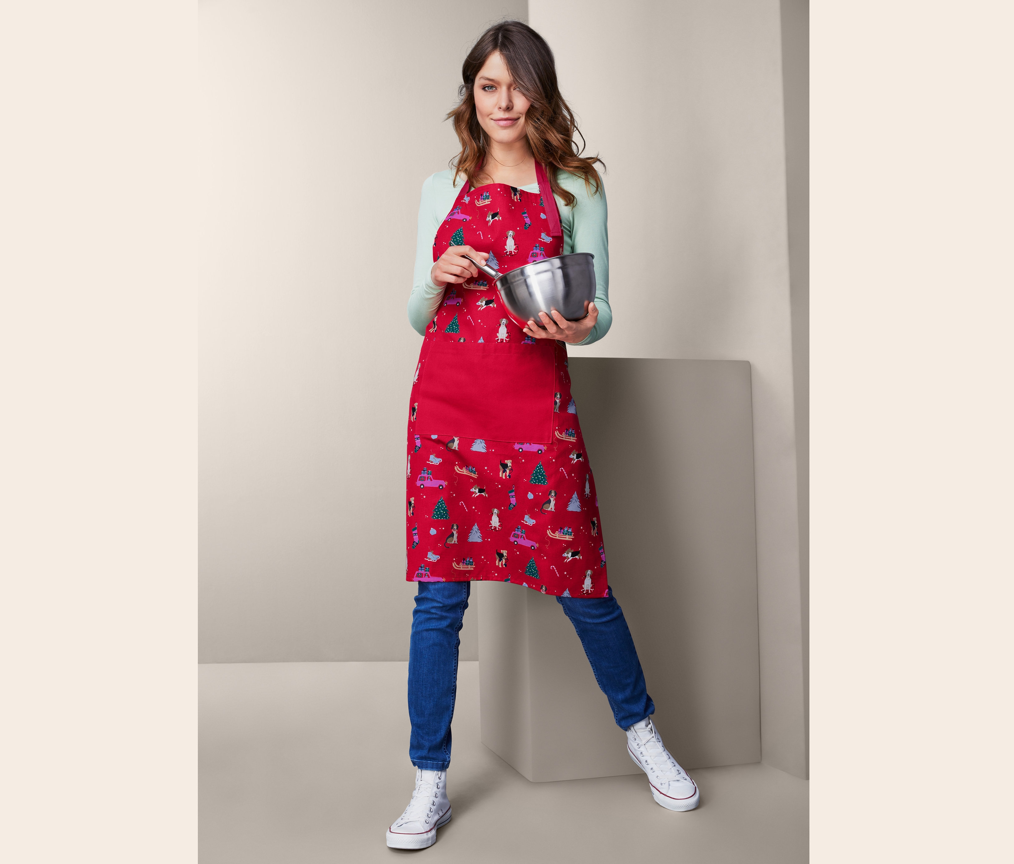 Mutfak önlüklü kadın bir kase ve çırpma teli tutuyor.