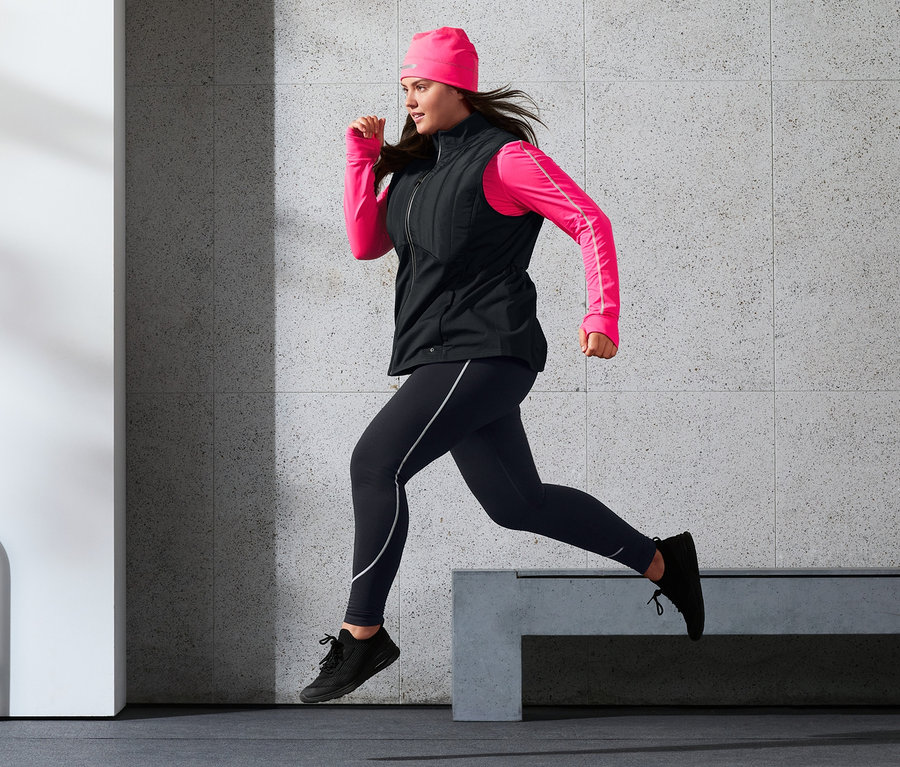 Kadın Thermo-Steppweste, Sporttight, Reflektör Baskılı Termal Bere ve neon pembe uzun kollu fonksiyonel tişört ile koşuyor.