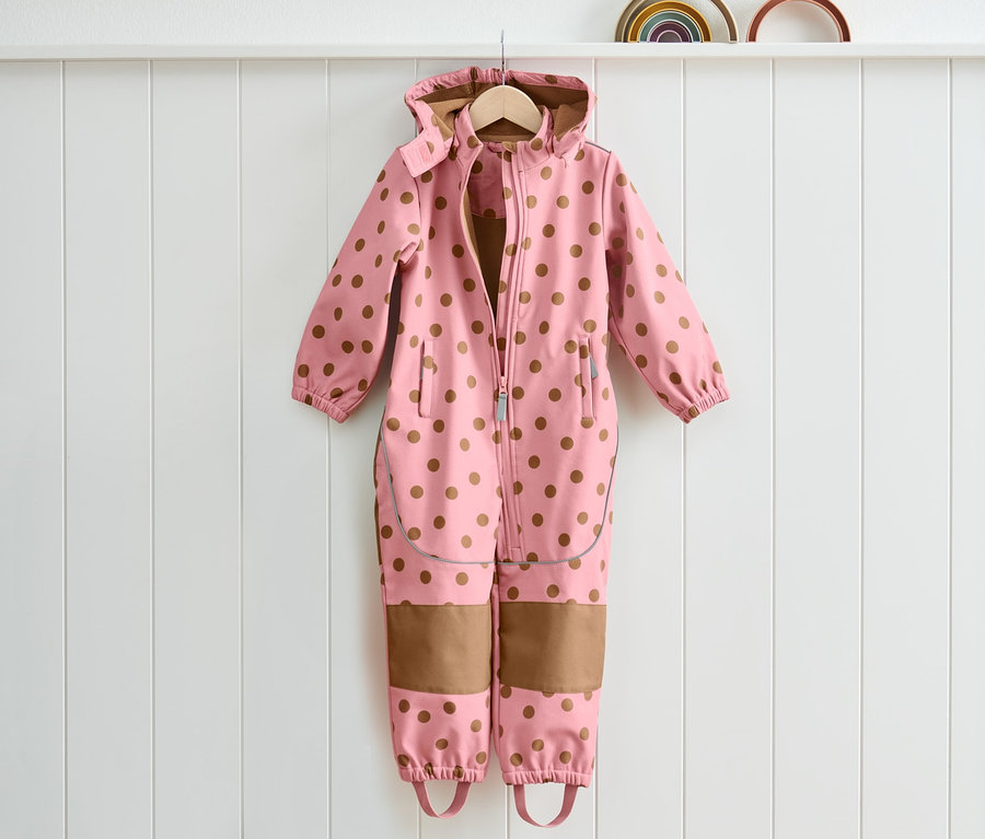 Askıda duran, kahverengi puantiyeli pembe softshell tulum.