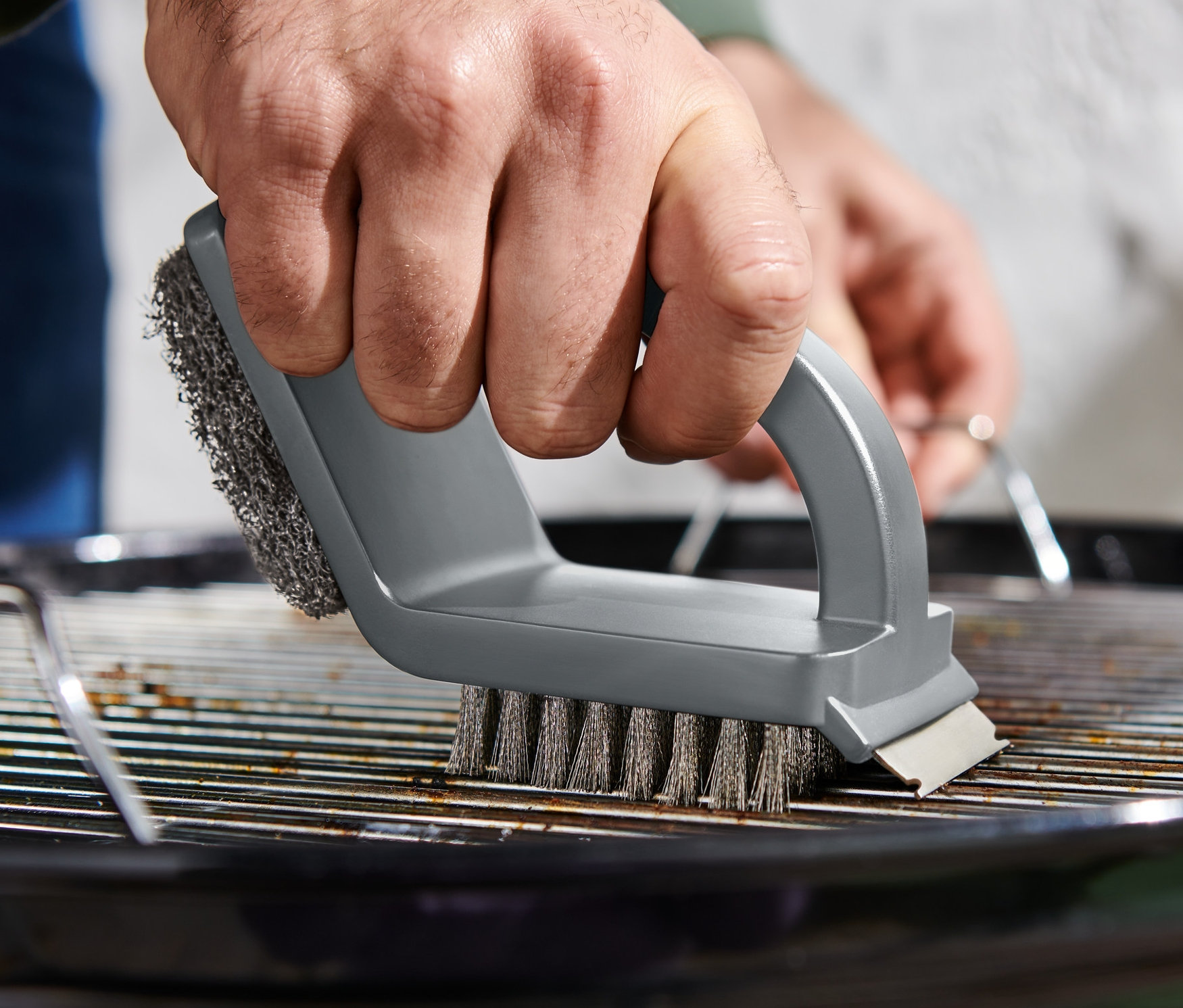 Adam 3'ü 1 Arada Temizlik Fırçası ile ızgara temizliyor.