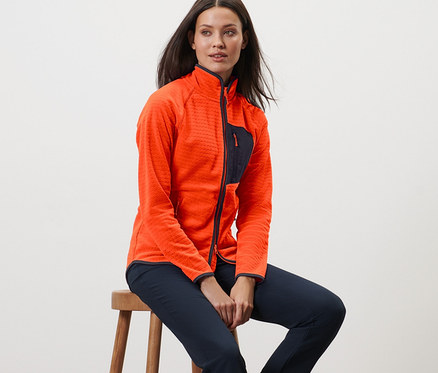 Kadın taburede oturuyor ve polar ceket giyiyor.