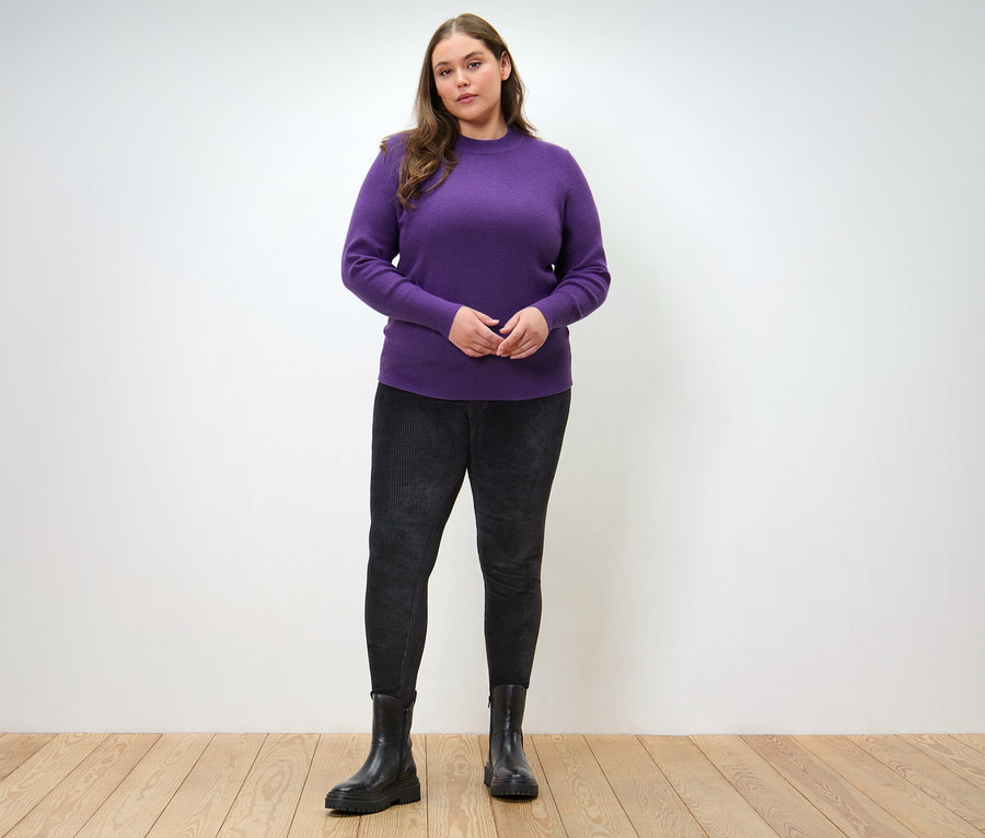 Kadın İnce Örgülü Kazak ve Kadife Tayt ile poz veriyor.