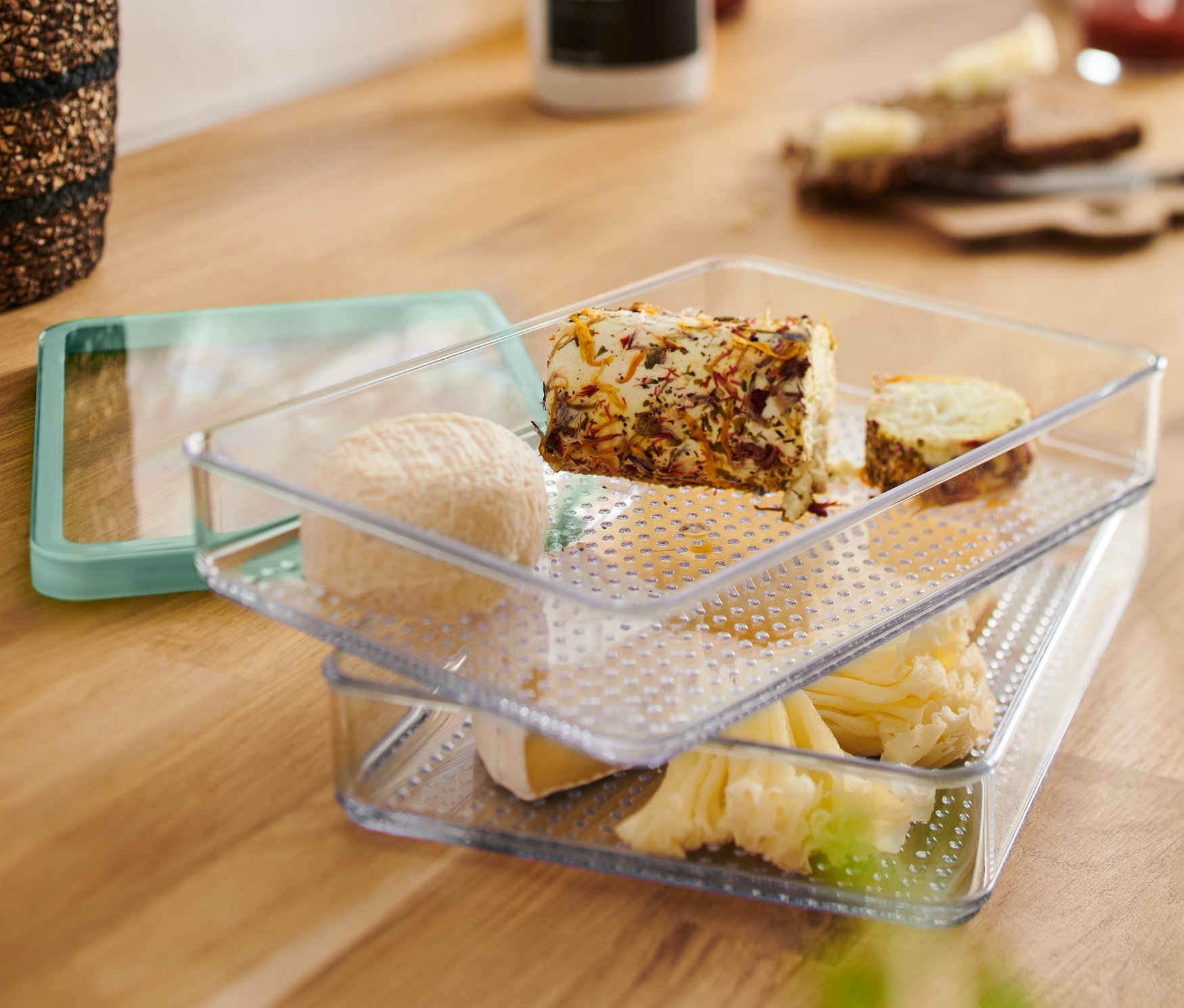 İki şeffaf Felvágottároló edény üst üste dizilmiş ve farklı peynirlerle doldurulmuştur.