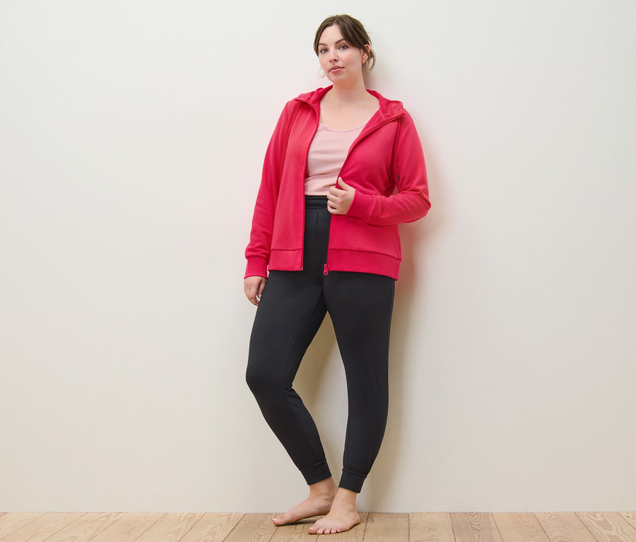 Kadın pembe Sweat Mont, Yoga Pantolonu ve 2 Adet Gül Kurusu/Pembe Atlet ile poz veriyor.
