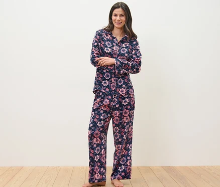 Ayakta duran bir kadın, çiçek desenli dokuma pijama takımı giyiyor.