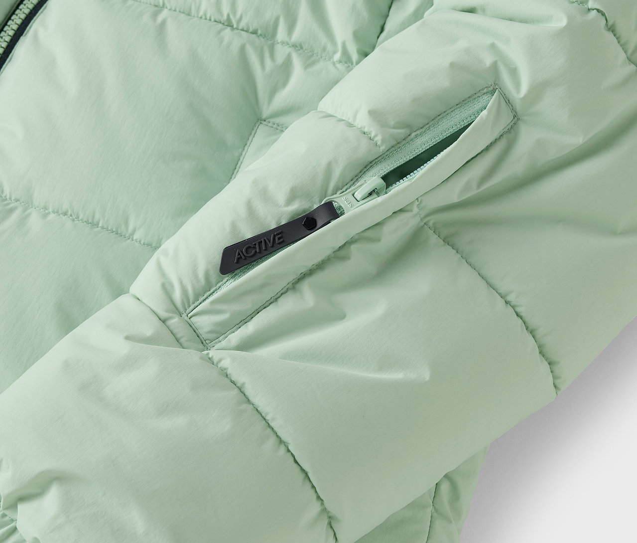 Fermuarlı cebi olan açık yeşil kapitone ceket detayı.