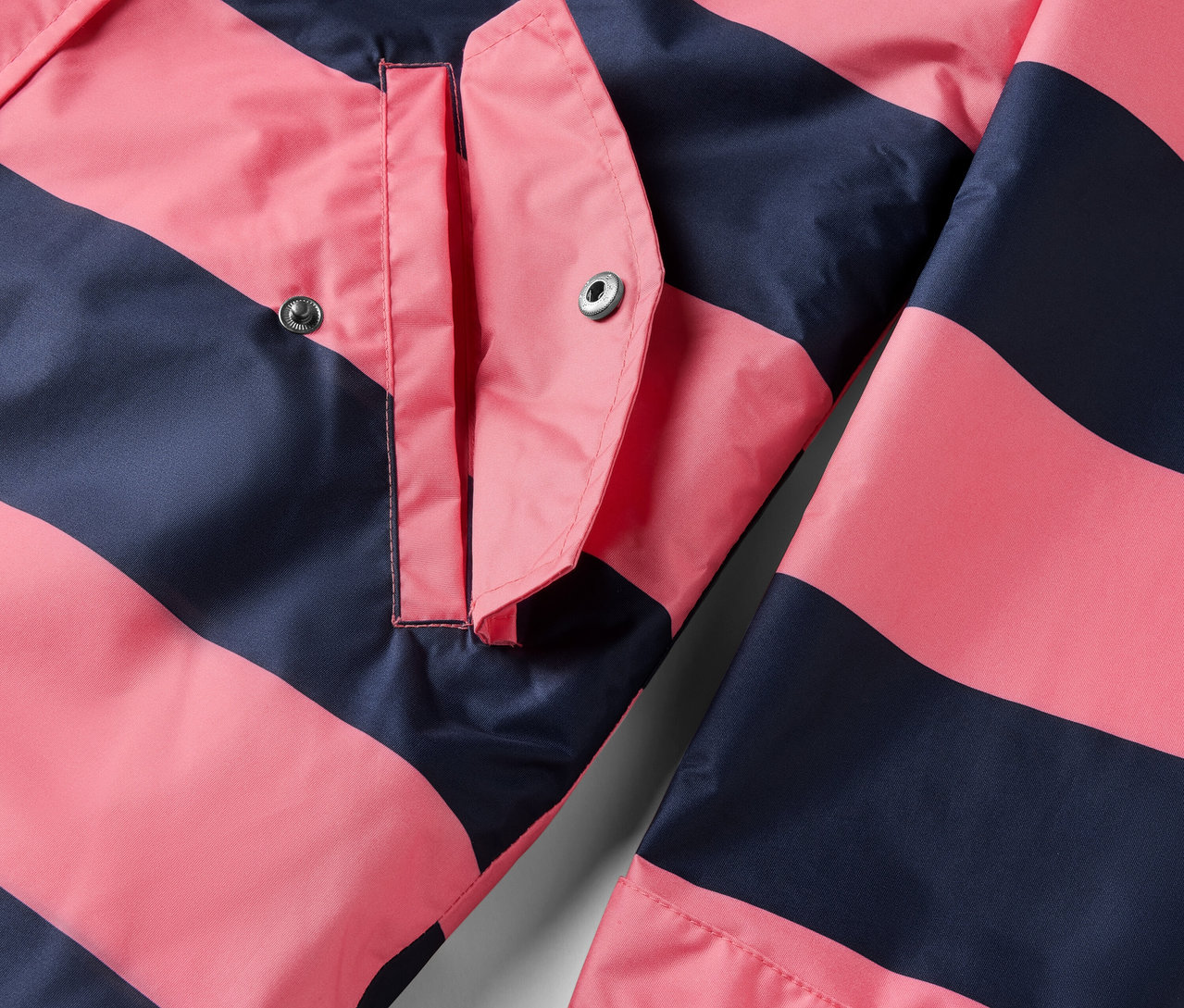 Pembe ve lacivert çizgili, cepli 3'ü 1 arada yağmurluk detayı.