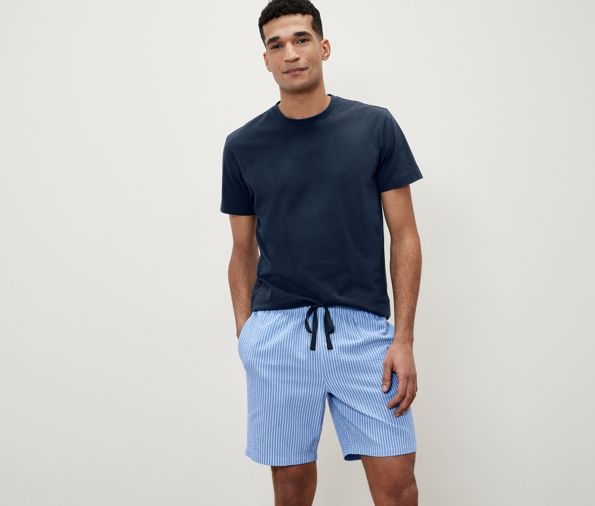 Adam, dokuma pantolonlu kısa pijama takımıyla poz veriyor.