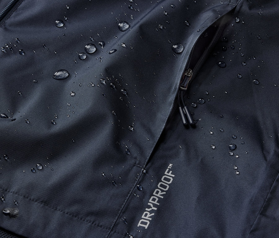 Fermuarlı cebi ve DRYPROOF yazısı olan lacivert bir yağmurluğun detayı.