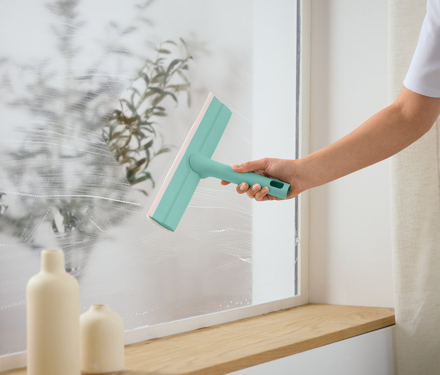 Bir kişi bir pencereyi cam sileceği ile temizliyor.