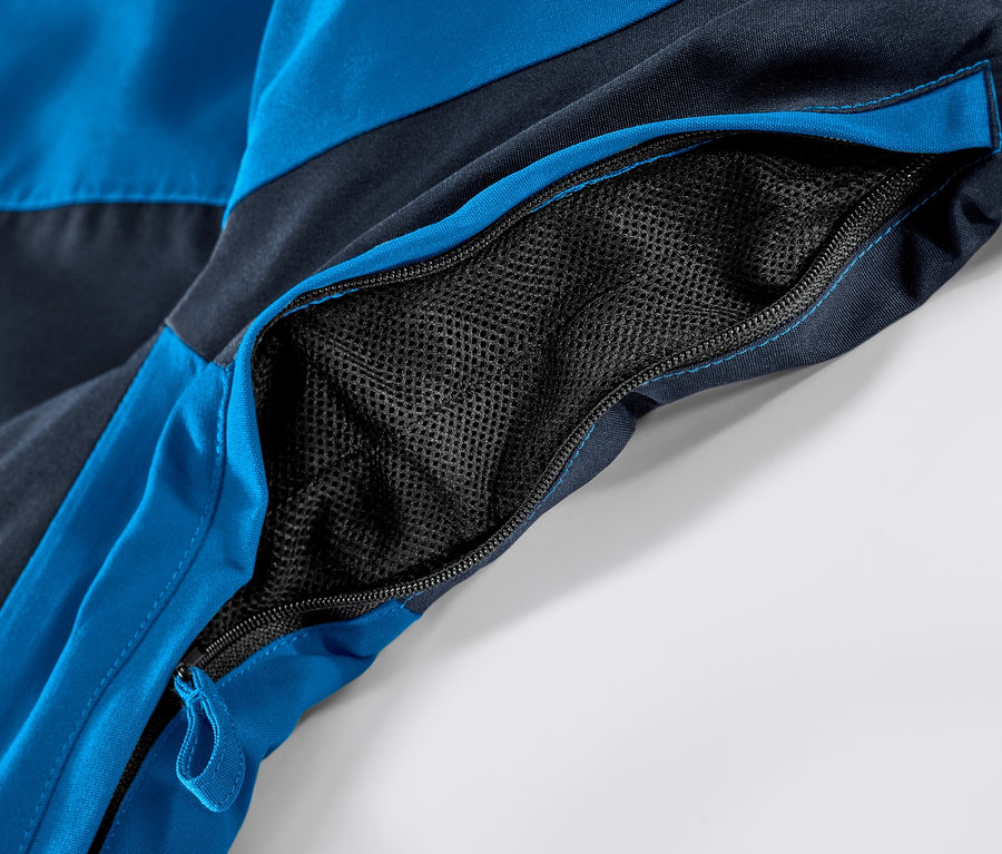 Açık fermuarlı cebi olan mavi kayak montunun detayı.