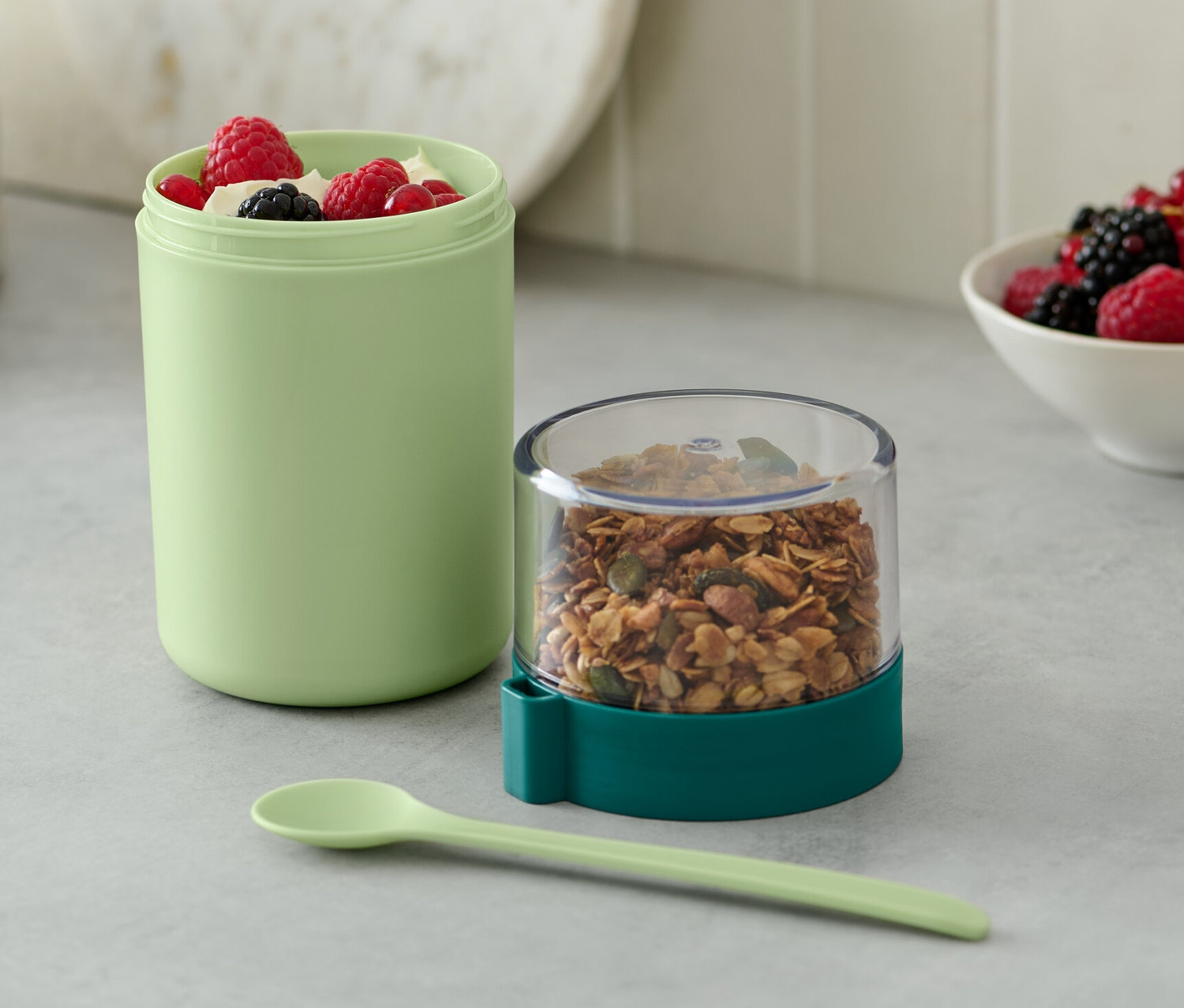 Yeşil renkli, müsli ve meyvelerle dolu taşınabilir yoğurt kabı.