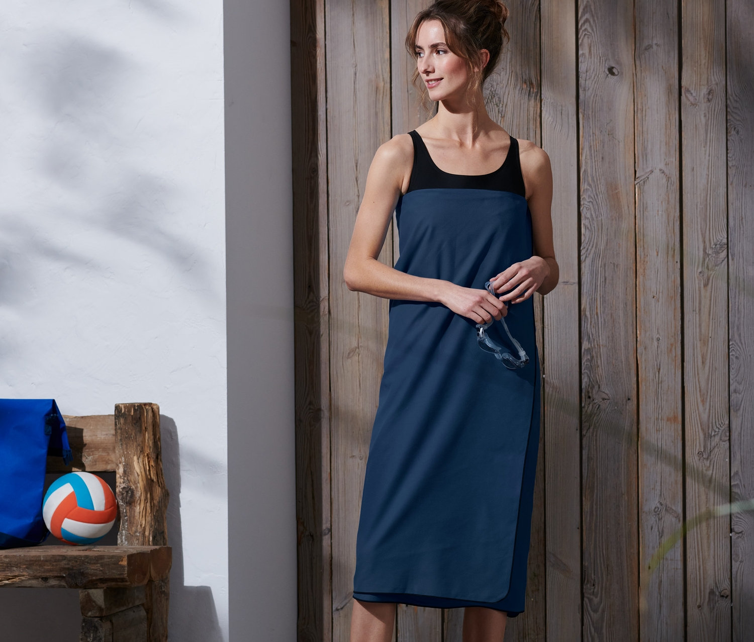 Ahşap zeminde duran ve XL Outdoor Banyo Havlusu, yakl. 100 x 180 cm'ye sarınmış bir kadın.