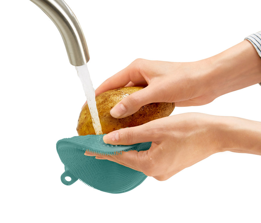 Bir kadın patatesi akan suyun altında 2 adet silikon bulaşık süngeri ile yıkıyor.