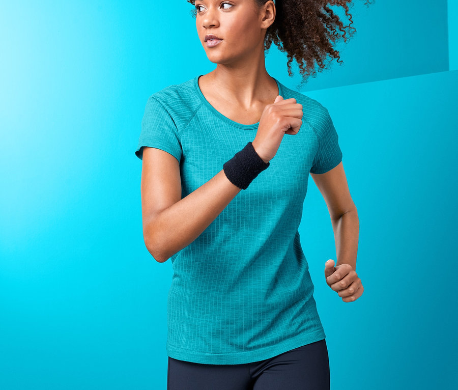 Kadın turkuaz dikişsiz fonksiyonel tişört ile koşuyor.