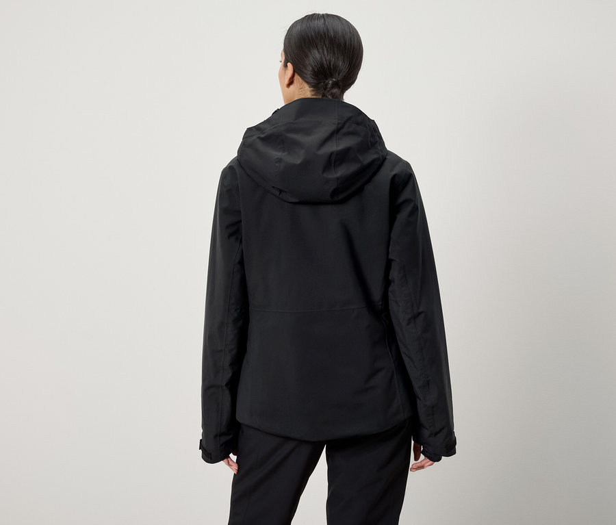 Arkadan at kuyruğu saçlı, siyah kapüşonlu ceket ve siyah pantolon giyen bir kadın görülüyor.