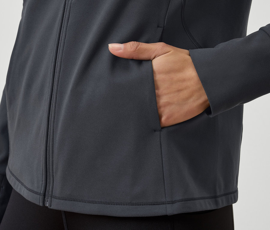 Gri fermuarlı bir sweatshirt'ün yakından çekilmiş görüntüsü, cebinde bir el var.