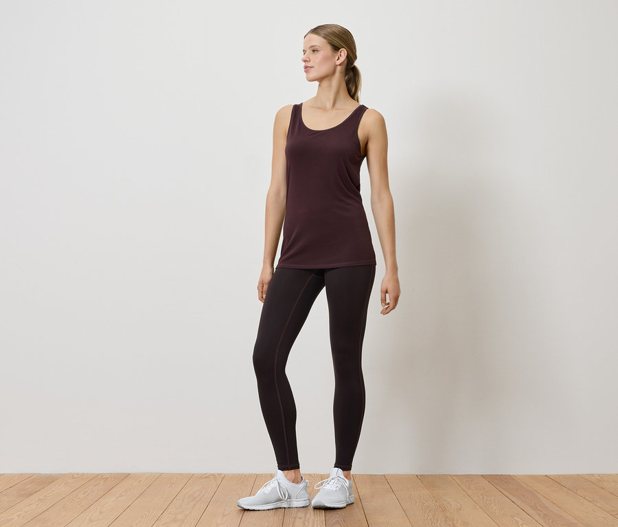 İç mekanda atlet ve taytlı bir kadın poz veriyor.