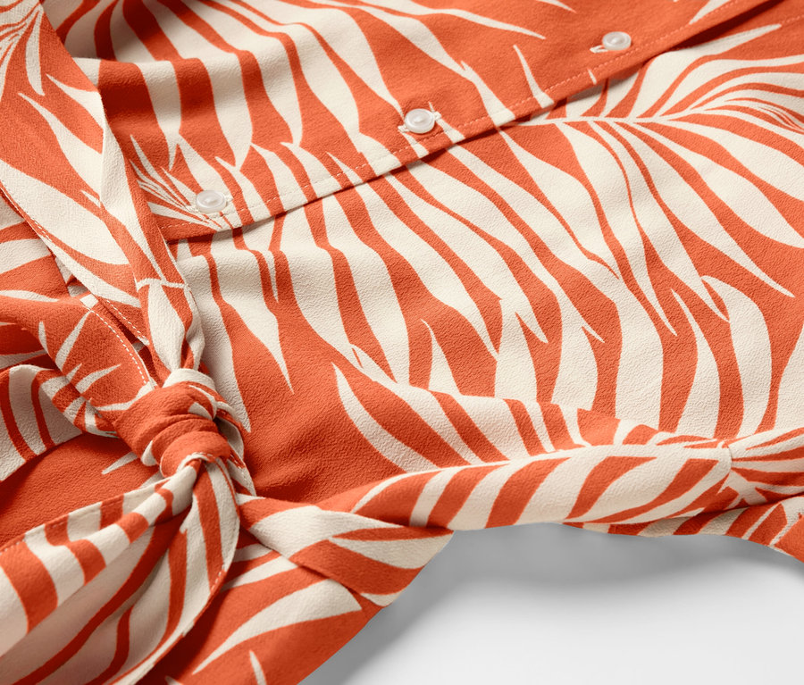 Düğmeleri ve bel bağı olan, desenli gömlek elbisenin detayı.