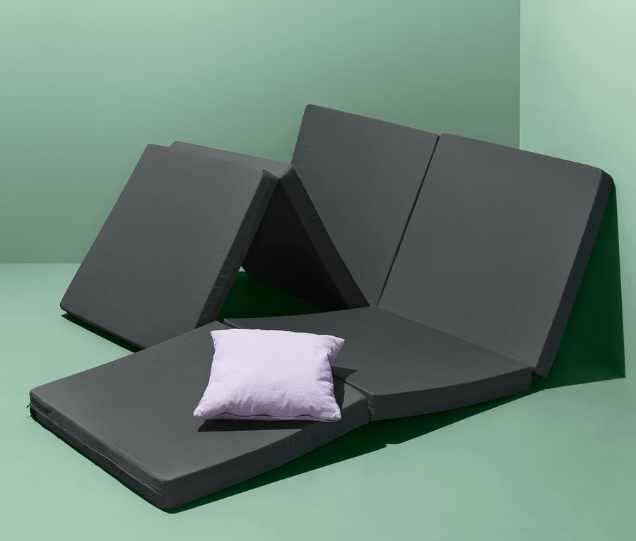 Çift kişilik misafir yatağı yeşil bir arka plan üzerinde kurulmuş, üzerinde mor bir yastık var.