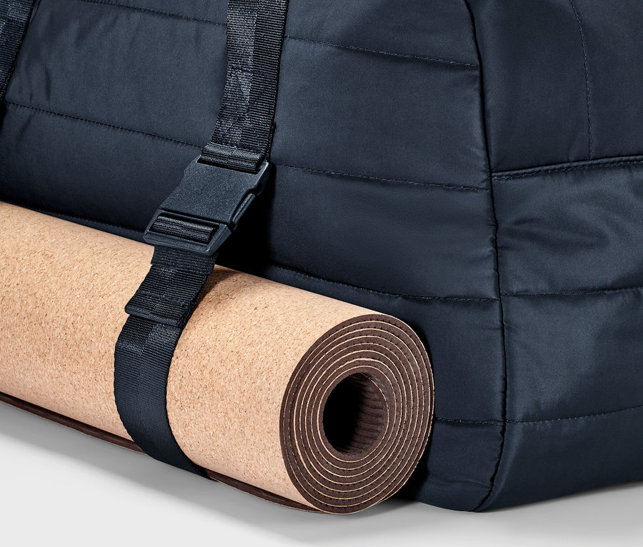 Kayışla tutturulmuş bir yoga matı ile bir spor çantasının parçası.