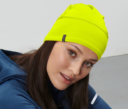 Kadın yerde oturuyor ve neon sarısı termal bere takıyor.