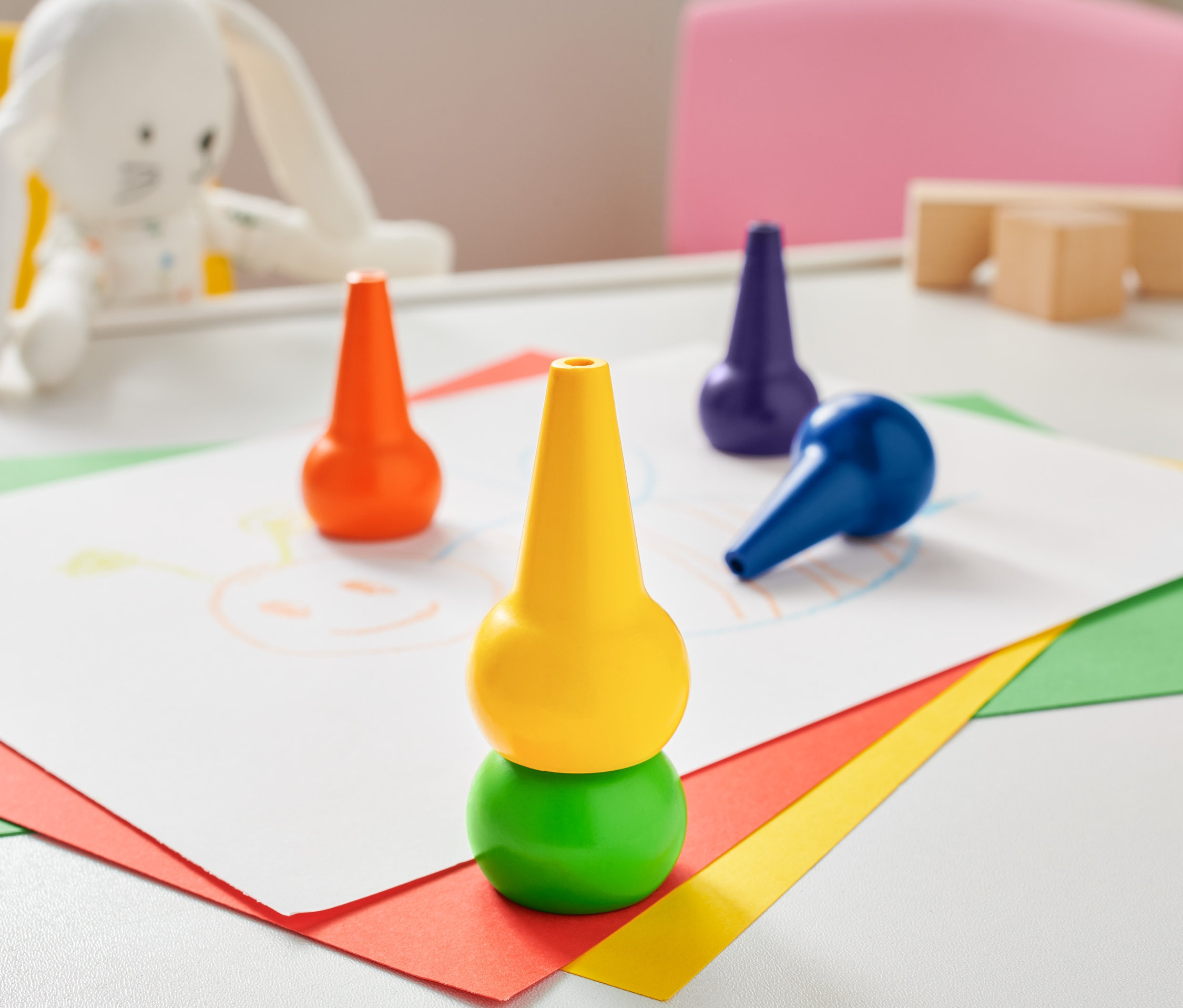 Masanın üzerinde 5 adet balmumu boya kalemi ve bir çizim bulunuyor.