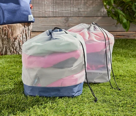 Çim üzerinde iki adet Outdoor File Çanta, arka planda bir sırt çantası.