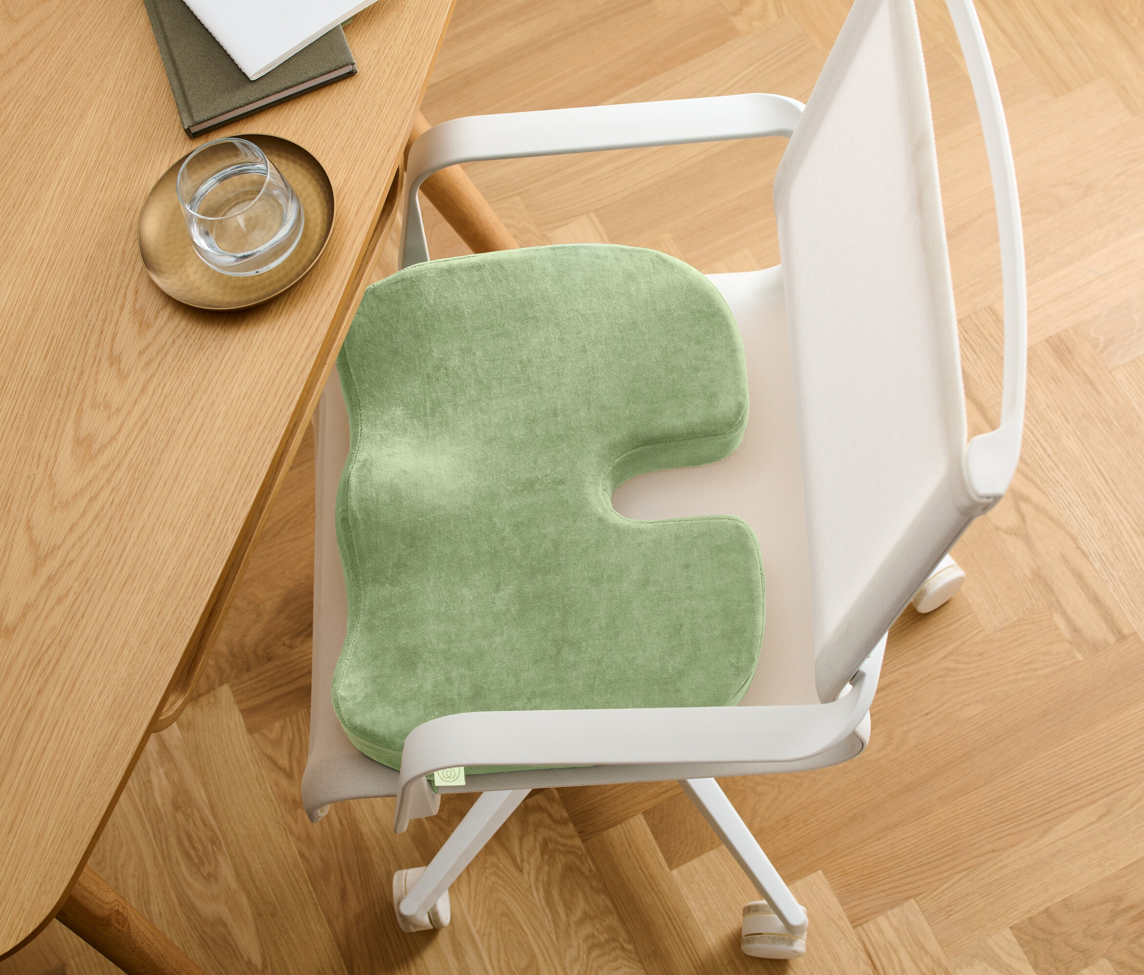 U şeklinde kesikli yeşil bir oturma minderi bir sandalyede. Sandalye ahşap bir masanın yanında duruyor.